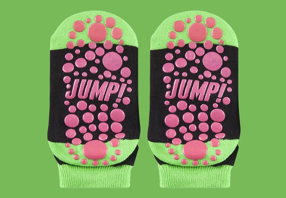 Children's black and green socks with pink non-slip dots and "JUMP!" on the soles.