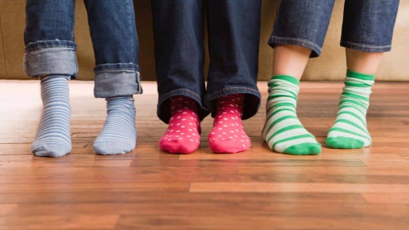 Three pairs of striped and polka-dotted socks with unique Sinoknit logos are showcased on a wooden floor.