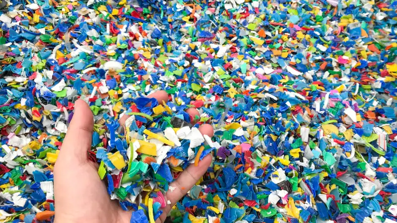 Vibrant multicolored confetti scattered across a surface, with a hand holding a handful of the tiny paper pieces. Perfect for festive occasions, parties, and decorative purposes, showcasing a lively a.