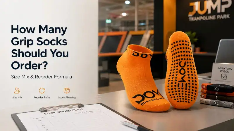Orange trampoline park grip socks with black branding and a stack of sock sizes on a table at Sinoknit.