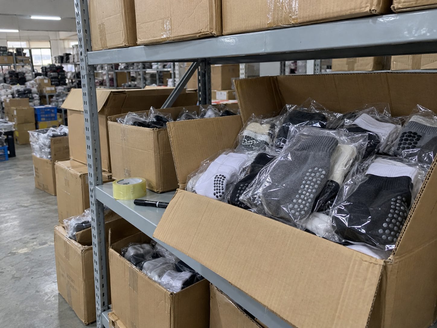 Bagged trampoline grip socks stocked in cartons on warehouse shelves, ready for wholesale orders